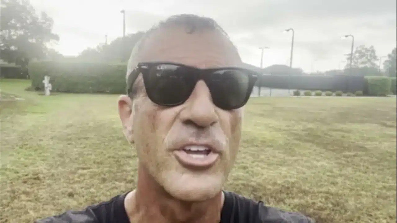 Close-up of a man wearing black sunglasses outdoors in a grassy park