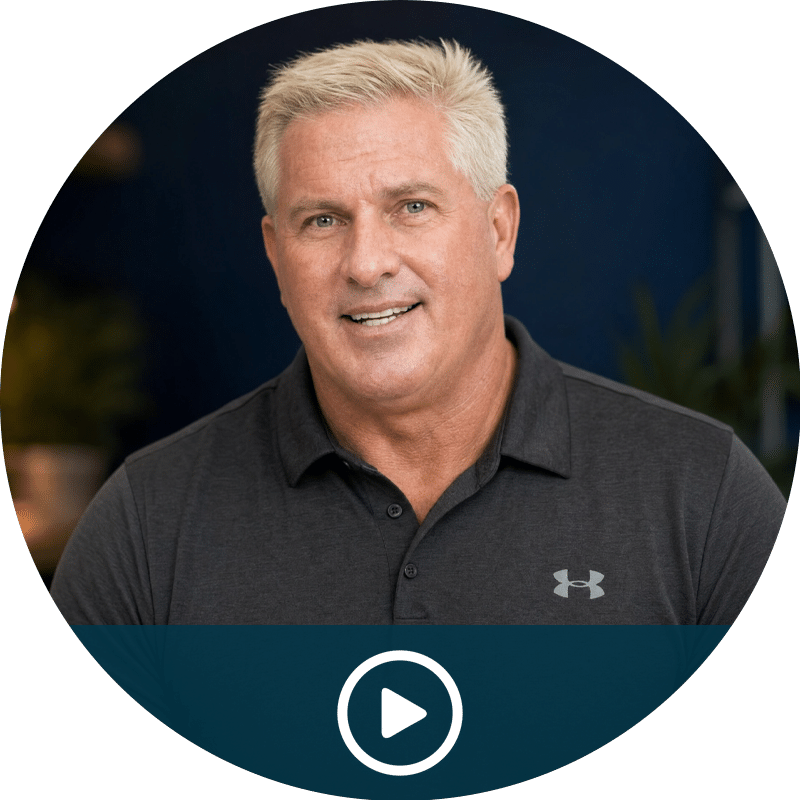 Video thumbnail: smiling man in a dark polo, ready to play (play button at bottom center).